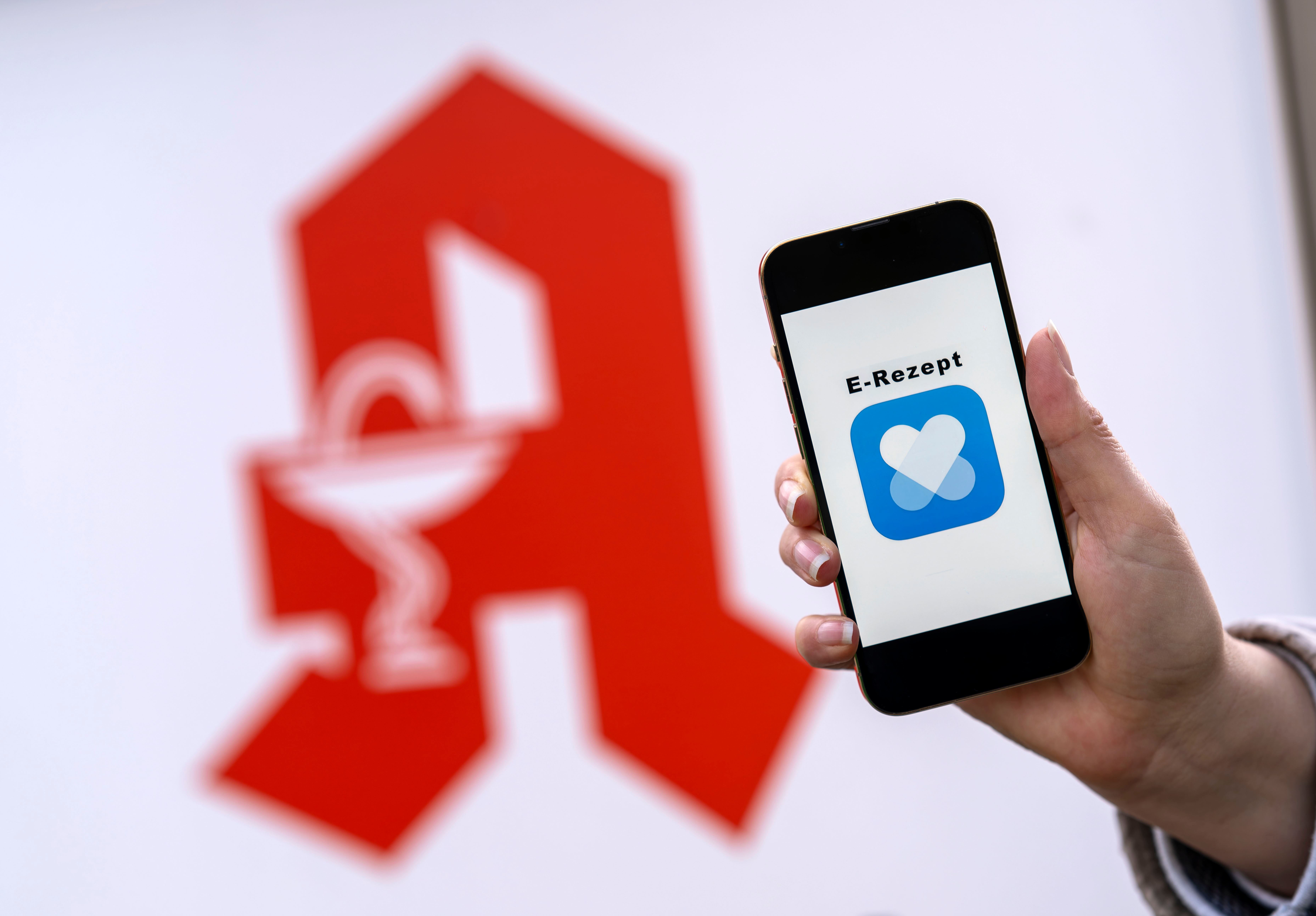 Im Hintergrund Apothekenzeichen, im Vordergrund Handy mit EPA im Screen